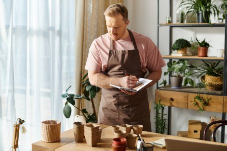 Un hombre en un delantal toma notas diligentemente en un portapapeles en una tienda de plantas, mostrando su dedicación a su pequeña empresa.