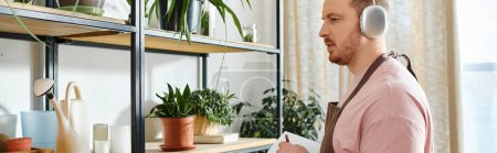 Un hombre elegante con auriculares se encuentra frente a un estante en una tienda de plantas, rodeado de exuberante vegetación y belleza botánica.