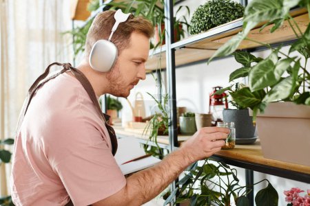 Téléchargez les photos : Un homme avec casque regarde une plante dans un magasin de plantes, incarnant l'essence de la nature et de la musique en parfaite harmonie. - en image libre de droit
