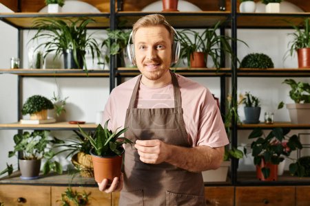 A man in an apron carefully holds a potted plant, showcasing his dedication to his small florist business.