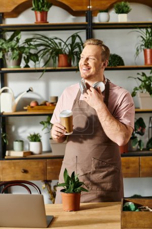 Un hombre en un delantal está sosteniendo una taza de café en una tienda de plantas, mostrando la esencia de ser dueño de una pequeña empresa.