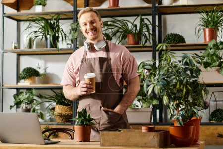 Un hombre en un delantal sosteniendo una taza de café. Él está en una tienda de plantas, lo que refleja un pequeño empresario tomando un descanso.