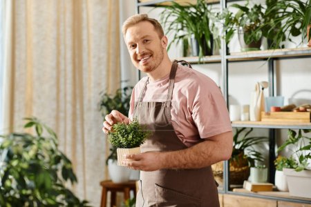 Foto de Un hombre en un delantal con amor sostiene una planta en maceta en un ambiente acogedor. - Imagen libre de derechos
