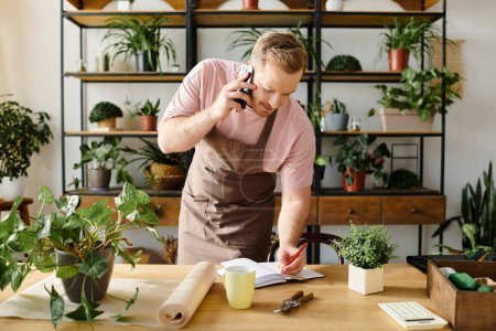 Un hombre en un delantal multitareas hablando en su teléfono celular mientras maneja su negocio de tienda de plantas.