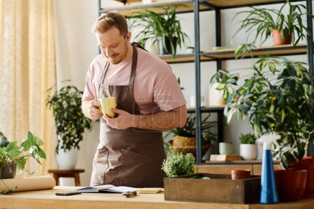 Photo for A handsome man in an apron relaxes, holding a steaming cup of coffee. - Royalty Free Image