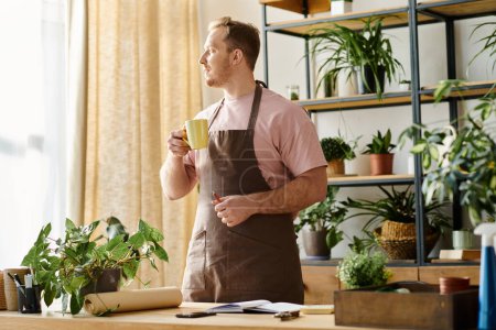 A handsome man in an apron enjoys a cup of coffee in a plant shop, embodying the essence of a small business owner.