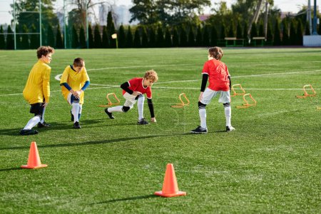 Foto de Un animado grupo de niños pequeños jugando enérgicamente un juego de fútbol en un campo de hierba, corriendo, pateando y animando mientras compiten en un partido amistoso. - Imagen libre de derechos