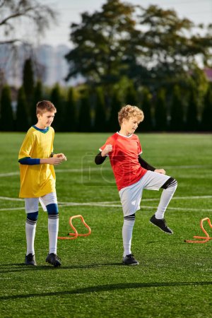 Téléchargez les photos : Deux jeunes garçons énergiques donnent joyeusement un coup de pied à un ballon de football, montrant leurs compétences et leur passion pour le sport. - en image libre de droit