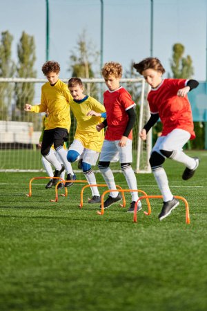 Téléchargez les photos : Un groupe de jeunes garçons jouant à un jeu énergique de football sur un terrain herbeux. Ils courent, donnent des coups de pied au ballon et s'encouragent mutuellement pendant qu'ils concourent. - en image libre de droit