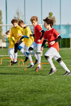 Téléchargez les photos : Un groupe de jeunes garçons jouant avec enthousiasme un jeu de football sur un terrain herbeux, courir, donner des coups de pied et passer le ballon avec excitation et concentration. - en image libre de droit