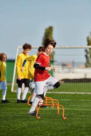 Dynamiczna grupa małych dzieci angażuje się w porywającą grę w piłkę nożną, kopiąc piłkę wokół boiska z entuzjazmem i pracą zespołową. Biegają, przechodzą i strzelają do celu, pokazując swoje umiejętności i koleżeństwo..