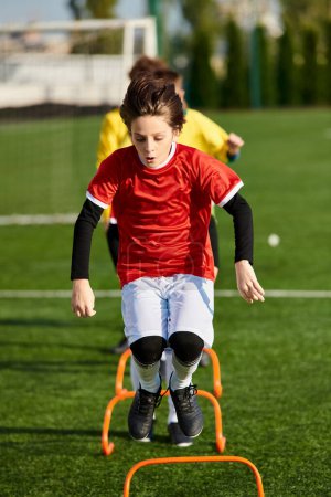 A young boy is energetically kicking a soccer ball across the green soccer field, showcasing his passion and skills in the sport. His concentration and determination are evident as he focuses on perfecting his technique.
