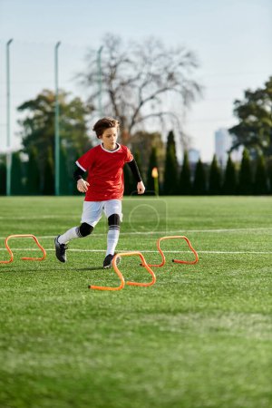 A young boy is skillfully kicking a soccer ball across a vast field, displaying agility and precision in his movements.