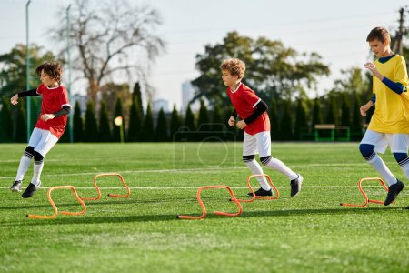 Téléchargez les photos : Un groupe animé de jeunes garçons engagés dans un jeu intense de soccer, de course, de coups de pied et de stratégie sur un champ d'herbe. - en image libre de droit