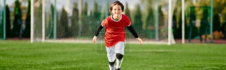 Foto de Una joven, vestida con un uniforme de fútbol, corre por el campo de hierba con determinación y rapidez, mostrando su pasión por el deporte. - Imagen libre de derechos