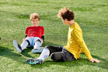 Téléchargez les photos : Deux jeunes garçons jouant énergiquement à un jeu de football sur le terrain luxuriant d'herbe verte. Ils sont engagés dans dribbler, passer, et donner des coups de pied au ballon, mettant en valeur leurs compétences et leur travail d'équipe. - en image libre de droit