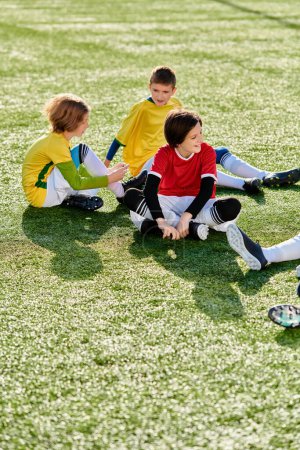 Eine Gruppe junger Jungen hockt freudig auf einem Fußballplatz, ihre Augen leuchten vor Aufregung und Vorfreude. Das grüne Gras unter ihnen kontrastiert mit ihrer pulsierenden Energie und schafft eine dynamische Szene, die sportlichen Spaß verspricht.