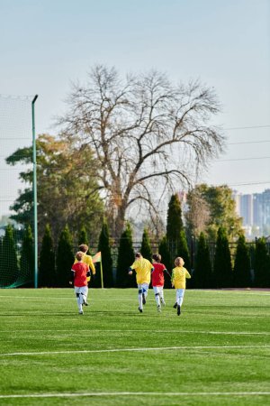 A vibrant scene unfolds as a group of young boys engage in a spirited game of soccer. They are kicking the ball, running, and strategizing as they play on a grassy field under the bright sun.