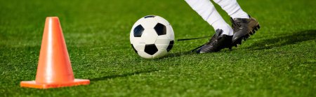 Una persona demuestra sus habilidades futbolísticas pateando una pelota de fútbol alrededor de un cono colocado en un campo. El jugador muestra precisión y agilidad en la maniobra de la pelota alrededor del obstáculo.