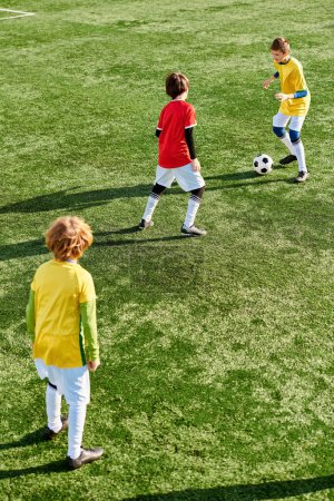 Téléchargez les photos : Un groupe de jeunes enfants énergiques jouent à un jeu amical de football sur un terrain herbeux, riant et courant après le ballon dans leurs maillots colorés et leurs crampons de football. - en image libre de droit
