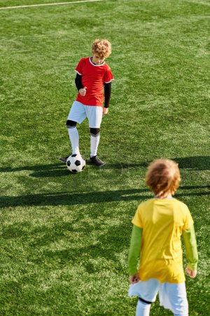 Téléchargez les photos : Un jeune garçon donne un coup de pied énergique à un ballon de football sur un terrain vert luxuriant, mettant en valeur son talent et sa passion pour le sport. - en image libre de droit