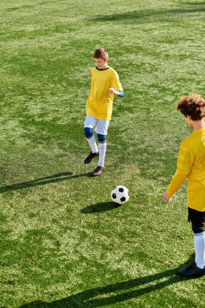 Deux jeunes hommes énergiques donnent un coup de pied enthousiaste à un ballon de football dans les deux sens sur un vaste terrain vert, leurs mouvements rapides et leur habile jeu de pieds mettant en valeur leur passion pour le sport.