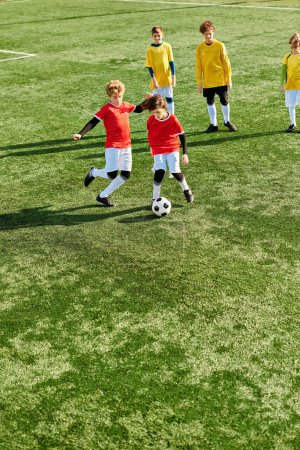 Grupa małych dzieci energicznie gra w piłkę nożną na trawiastym polu. Biegają, dryblują, podają i kopią piłkę z entuzjazmem i pracą zespołową.