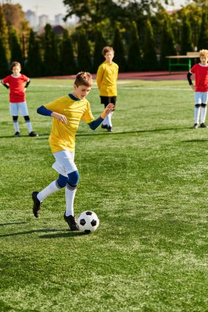 Grupa młodych chłopców energicznie zaangażowanych w grę w piłkę nożną, biegających po trawiastym polu, kopiących piłkę, przechodzących i dopingujących się nawzajem.