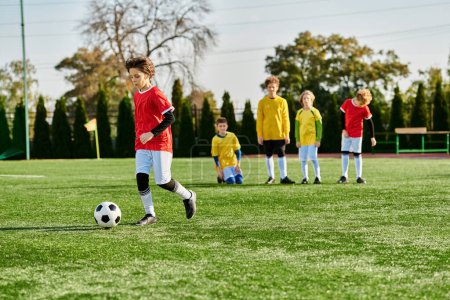 Grupa małych dzieci, wypełniona radością i entuzjazmem, angażuje się w porywającą grę w piłkę nożną. Biegają, kopią i podają piłkę, pokazując ducha drużyny i koleżeństwo na boisku..