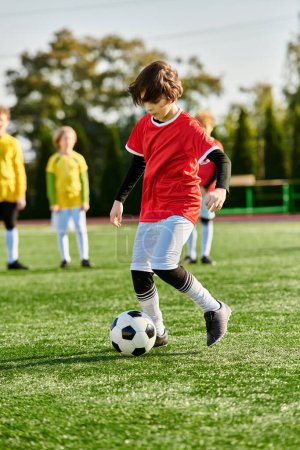 A young boy is kicking a soccer ball on a green field, showcasing his skills and passion for the sport. The boy is focused on the ball as he kicks it, displaying agility and enthusiasm in his movements.