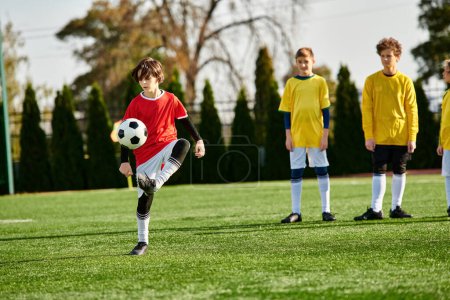 Téléchargez les photos : Un jeune garçon donne un coup de pied énergique à un ballon de football sur un terrain vert. Son expression concentrée et son mouvement fluide capturent l'excitation et l'intensité du jeu alors qu'il perfectionne ses compétences. - en image libre de droit