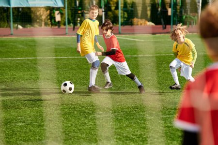 Téléchargez les photos : Un groupe animé de jeunes enfants jouent à un jeu de football sur un terrain vert. Ils courent, donnent des coups de pied et passent le ballon dans un match amical rempli de rire et d'excitation. - en image libre de droit
