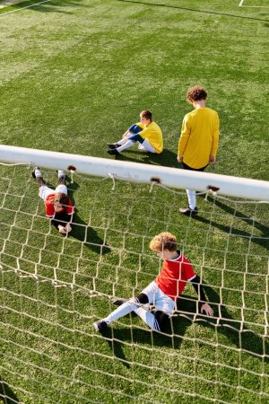 Eine Gruppe junger Männer sitzt triumphierend auf einem Fußballplatz und genießt eine wohlverdiente Pause nach einem Spiel. Sie plaudern, lachen und feiern ihren Sieg.