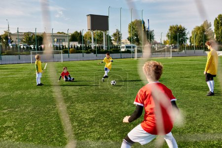 Grupa małych dzieci grają energiczną grę w piłkę nożną na trawiastym polu. Biegają, podają i kopią piłkę z podnieceniem i pracą zespołową. Dzieci śmieją się i dopingują podczas przyjacielskich zawodów..