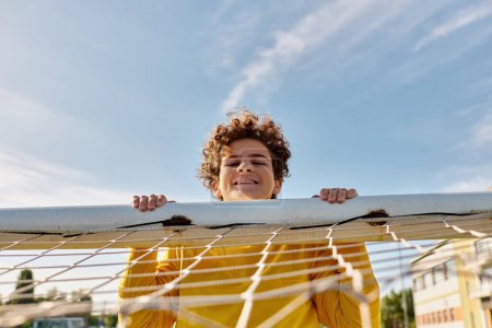Téléchargez les photos : Un moment paisible capturé alors qu'un jeune garçon tient délicatement une planche de surf au-dessus d'un hamac, incarnant l'esprit insouciant de l'été sur la plage. - en image libre de droit