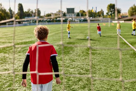 Grupa młodych chłopców radośnie gra w piłkę nożną, biegnie, przechodzi i kopie piłkę na zielonym polu w jasnym słońcu.