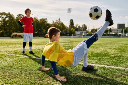 Téléchargez les photos : Un jeune garçon plein d'esprit donne un coup de pied énergique à un ballon de football sur un terrain vert luxuriant, mettant en valeur son talent et son amour pour le sport. - en image libre de droit