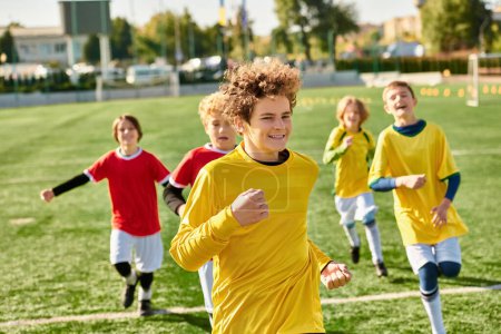 Téléchargez les photos : Un groupe animé de jeunes garçons qui courent joyeusement autour d'un terrain de soccer, donnent des coups de pied au ballon, rient et se poursuivent dans une compétition amicale. - en image libre de droit