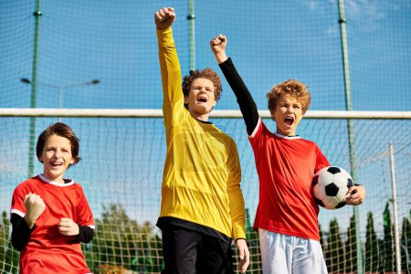 Photo for A group of energetic young boys stand triumphantly on top of the soccer field, celebrating their victory. The green grass and white lines of the field create a vibrant backdrop as the boys bond over their shared love for the sport. - Royalty Free Image