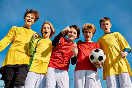 Un animado grupo de jóvenes se mantiene estrechamente unido, sosteniendo una pelota de fútbol con entusiasmo y camaradería. Sus rostros reflejan emoción y unidad mientras se preparan para un partido amistoso.