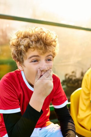 Un jeune garçon à l'expression dispendieuse s'assoit sur un banc, la main doucement posée sur sa bouche.