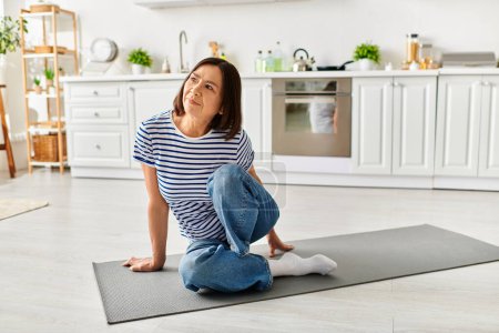 A mature beautiful woman in cozy homewear practicing yoga on a mat in a sunlit kitchen.
