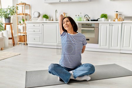 Woman in cozy homewear practicing yoga on a mat in a kitchen.