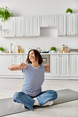 Eine reife Frau in gemütlicher Hausbekleidung praktiziert Yoga auf einer Matte in ihrer Küche.