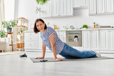 Eine reife schöne Frau in Hauskleidung praktiziert friedlich Yoga auf einer Matte in ihrem Wohnzimmer.