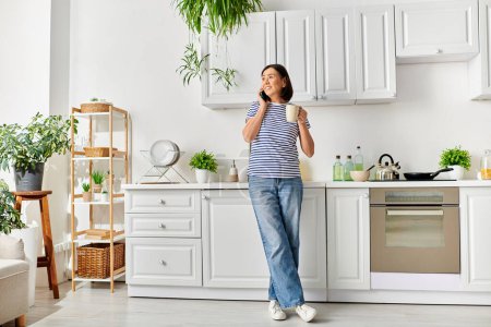 A mature woman in cozy homewear enjoying a moment in her kitchen, holding a cup.