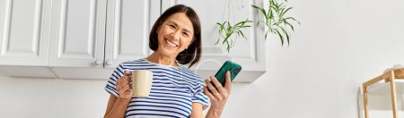 Una mujer en acogedora multitarea de ropa de casa con una taza de café y un teléfono celular.