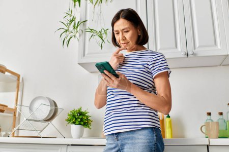 Mujer en ropa de casa acogedora se compromete con la tableta en la cocina moderna.