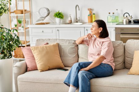Photo for A mature woman relaxes on a couch in her cozy living room. - Royalty Free Image