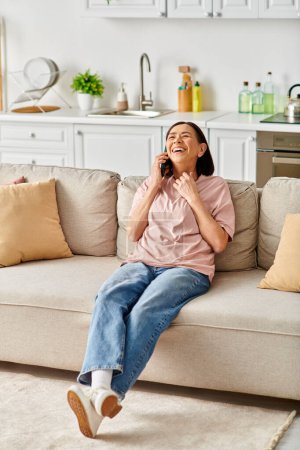 Mature woman in homewear talking on cell phone while sitting on couch.